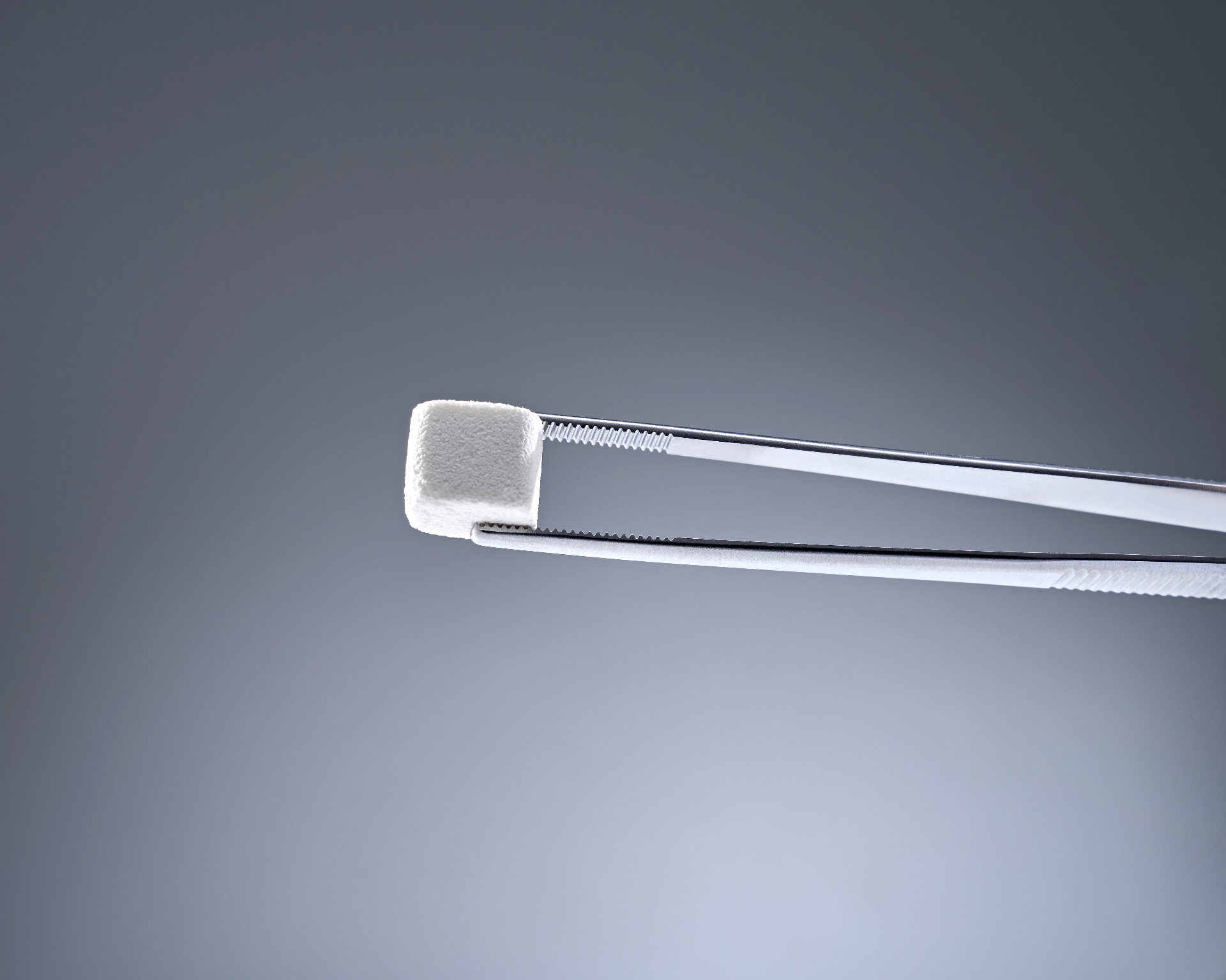 Bloco The Graft Collagen em close-up com pinça clínica